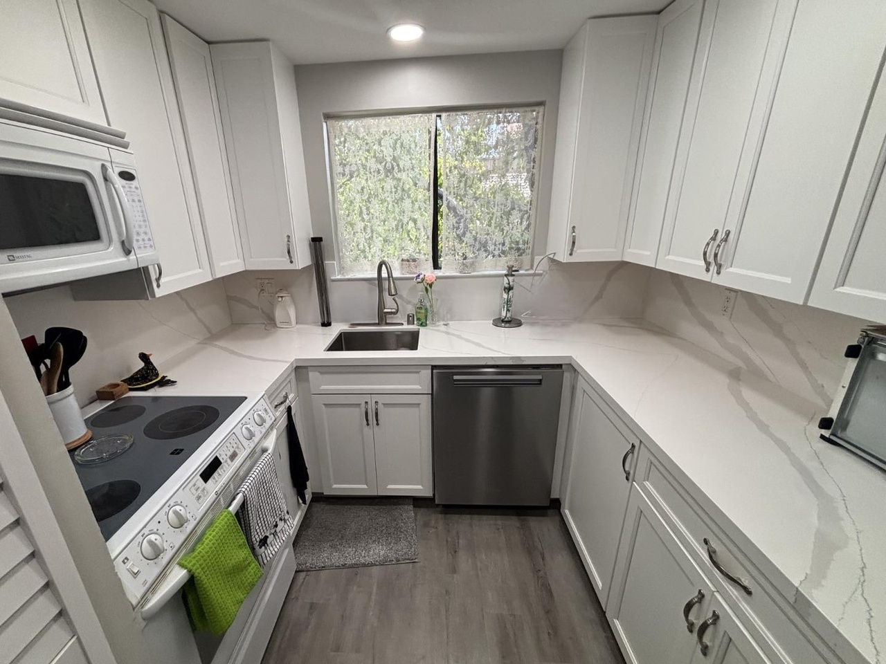 Remodeled white kitchen with stainless dishwasher and window